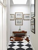 Gallery of pictures in hallway with cowhide rug on chequered floor