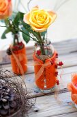 Rosen in Glasvasen dekoriert mit orangefarbenen Vasenmanschetten aus Filz