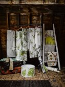 Lengths of fabric with various patterns of leaves hanging from clothes rack and ladder