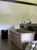 Stone bathtub in simple bathroom with concrete walls and floor