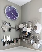 Kitchen utensils and clock hung on walls painted pale grey