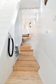 Wooden platform in narrow hallway and steps leading to cot with canopy in houseboat
