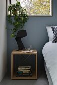 Stacked books in cubic bedside table with designer lamp on top