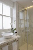 Elegant bathroom in white marble with glass shower screen and countertop basin