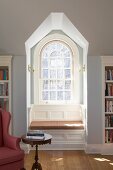 Comfortable, sunny window seat in niche of arched window in library