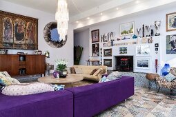 Indigo sofa, round coffee table, framed pictures and collection of trophies in modern interior