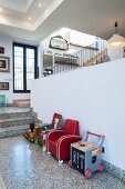 Retro children's armchairs and toys in front of half-height wall in open-plan interior with terrazzo floor