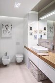 Modern pictures in designer bathroom with ample storage space in fitted cupboards and washstand base unit