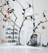 Larch branches with cones and stars arranged in three old glass vases decorated with adhesive letters