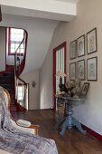 Elegant console tables and gallery of pictures in foyer of 18th-century, French country house in shades of red and grey