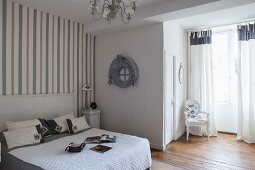 French-style, grey and white bedroom with striped wallpaper and Baroque chair