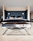 Bed with black upholstered headboard and chrome bench with animal-skin cover in masculine bedroom