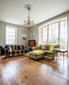 Velvet sofas on wooden floor and large, arched window in spacious living room