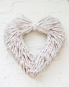 Heart-shaped wreath of whitewashed straw hung on wall