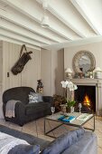 Open fireplace, grey sofas and exposed ceiling beams in living room