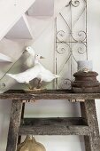 Stuffed geese and candle in wooden candle holder on rustic wooden table below staircase