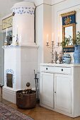 Simple, white-painted cabinet next to fireplace with blue and white tiles in rustic interior