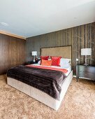 Doppelbett mit hohem Kopfteil, vor tapezierter Wand mit Birkenwaldmotiv im Schlafzimmer mit flauschigem Teppichboden