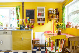 Colourful chairs in yellow kitchen-dining room with chequered floor