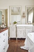 Antique white cabinet used as washstand with modern countertop basin below mirrors on bathroom wall
