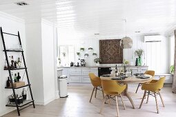 Runder Esstisch aus Holz Retro Stühlen in offenem Wohnraum, Wand und Decke mit weisser Holzverschalung