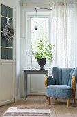 Blue 50s armchair next to geranium on table below window