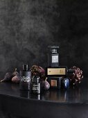 Gothic arrangement of black perfume bottles, figs and artichokes on table