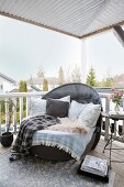 Cushions, fur rug and blankets on lounge chair on roofed terrace