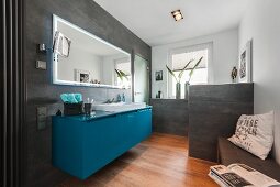 Zeitgenössisches Bad mit petrolfarbenem Waschtisch unter Spiegel, an Wand und Brüstungsmauer graue Fliesen