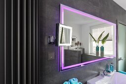 Wandspiegel mit integrierter LED Beleuchtung in Pink, an grau gefliester Wand