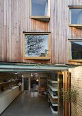 Holzfassadenausschnitt mit ausgedrehten Fenstern und Blick in offene Küche