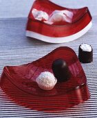 Zwei rote geschwungene Schälchen mit Süßigkeiten auf schwarz-weiß gestreiften Untergrund