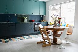 Küche mit zweifarbigen Fronten und rundem Esstisch mit Designerstühlen