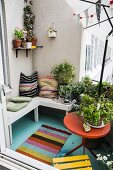 Cushions on wooden bench and potted plants on balcony