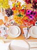 Laid table with lavish floral decorations in yellow and red tones, menu cards and speckled table runner