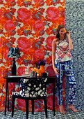 Young woman in room with different patterns on wallpaper, carpet, armchair and clothes