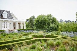 Geometric gardens with clipped hedges and elegant country house in background