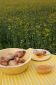 Croissants and jam on table in field of flowering rapeseed