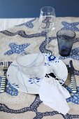 Festive place setting in blue and white on embroidered tablecloth