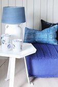 Blue and white table lamp on side table next to floor cushion