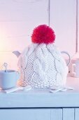 A handmade knitted tea cosy with a pompom