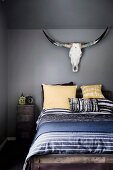 Schlafzimmer mit dunkelgrauer Wand, Tiertrophäe über das Bett