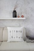 White scatter cushion with printed arrow motif on leather sofa