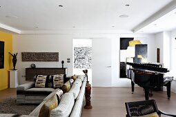 Moderner Wohnraum mit Sofakombination und Klavier vor modernem Bild