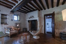 Kamin im Wohnzimmer mit Fliesenboden, gestrichener Natursteinwand und rustikaler Holzbalkendecke