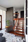 Staircase with wooden treads on metal frame and stone-flagged floor in retro hallway