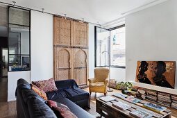 Palettentisch und schwarze Ledersofakombination im Wohnzimmer mit marokkanischem kunsthandwerklichem Holzelement