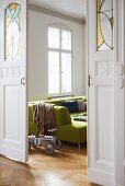 Artistic sliding doors with leaded glass panels in period apartment with green sofa