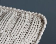 A knitted cushion with an offset ribbed pattern and a crocheted edge (detail)