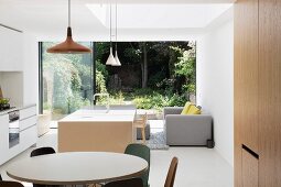 Open-plan, designer-style interior with open sliding French doors and view into green, summery garden